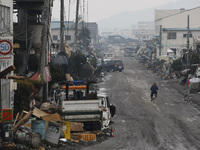 March 21, 2011-Ofunato, Japan-Bike man ride on debris and mud covered at Tsunami hit Destroyed Industrial Area in Ofunato on March 21, 2011,...