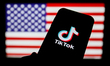 TikTok logo is seen displayed on a phone screen with American flag in the background in th...