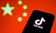 TikTok logo is seen displayed on a phone screen with Chinese flag in the background in thi...