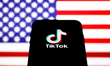 TikTok logo is seen displayed on a phone screen with American flag in the background in th...