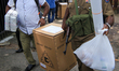 Sri Lankan election officers and police officers wearing protective masks carry  ballot bo...