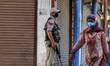 A woman walks past a policeman near a checkpoint in Sopore Town of District baramulla, Jam...