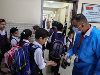 A Palestinian staff member provides disinfectant to a student in the rosary sisters school gaza , on the first day of a new school year, as...
