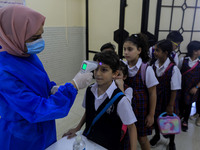A Palestinian staff member checks a student temperature in the rosary sisters school gaza , on the first day of a new school year, as Palest...