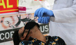 A health worker collects a nasal swab sample from a patient for Covid-19 rapid antigen tes...