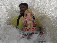 A Volunteer immerses an idol of the Hindu god Ganesha, into the Arabian Sea during the Ganesh Chaturthi festival in Mumbai, India on August...