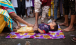 A child is laid down in front of the procession to perform a traditional act to get a bett...