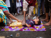A child is laid down in front of the procession to perform a traditional act to get a better life and the future in Dhaka, Bangladesh, on Au...
