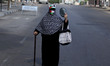  A Palestinian woman covers her face with a Palestinian flag amid the ongoing coronavirus...