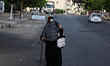  A Palestinian woman covers her face with a Palestinian flag amid the ongoing coronavirus...