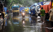 Commuters make their way along a waterlogged street following monsoon rainfalls in Dhaka,...
