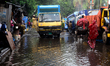 Commuters make their way along a waterlogged street following monsoon rainfalls in Dhaka,...