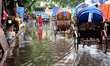 Commuters make their way along a waterlogged street following monsoon rainfalls in Dhaka,...