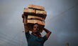 A labor carries goods as he loads on a boat in Dhaka, Bangladesh on September 1, 2020.  
