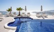 Swimming pool in a 5-star hotel resort with sun deck chairs and towel looking over a beaut...