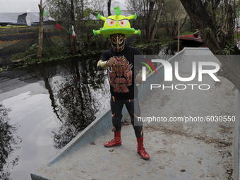 Dagma, a member of Chinampaluchas, on board a boat wears a hat with the figure of the coronavirus during a wrestling function in Chinampa on...