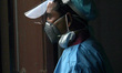 A health worker in personal protective equipment (PPE) waits for employees during nasal sw...