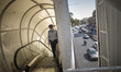 An Iranian man wearing a protective face mask stands on an escalator of a bridge in northe...