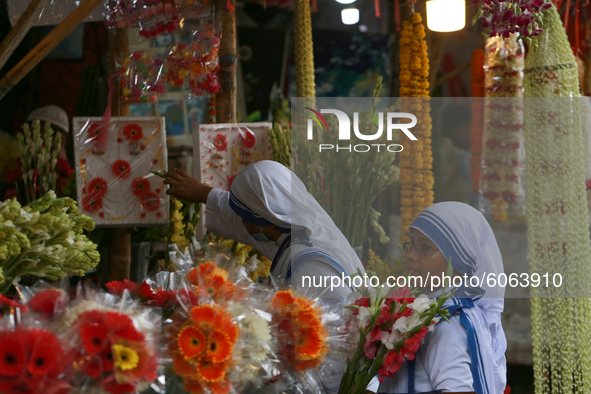 Women buy flowers from a stall in Dhaka, Bangladesh on October 6, 2020. 