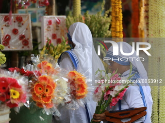 Women buy flowers from a stall in Dhaka, Bangladesh on October 6, 2020. (