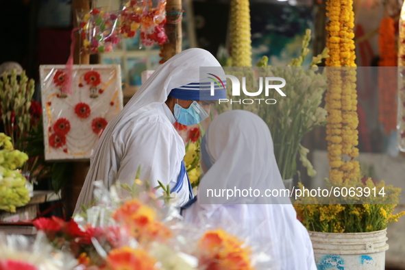 Women buy flowers from a stall in Dhaka, Bangladesh on October 6, 2020. 
