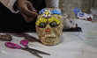 A worker making amaranth skulls, he decorates them with raisins, blueberries and sweets fo...
