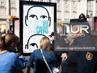 Demonstrators in front of an advertising poster to see the passage of the parade where you can read "Desiring to see masks" in front of the...
