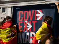 Demonstrators uploaded to an advertising poster to see the passage of the parade where "Covid Exit Madrid" can be read in front of the Royal...