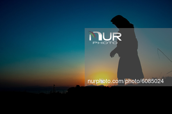A signle lady walks in the hills of Lesvos island to avoid the police. Silhouettes of walking refugees and migrants on the hills early in th...