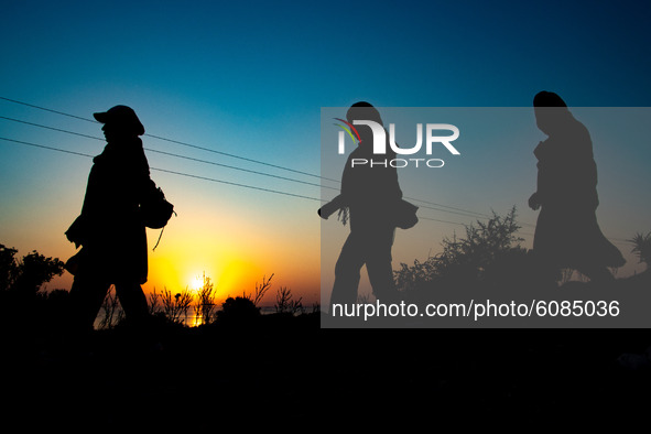 Group of ladies walking early in the morning towards former Moria Camp via the mountains. Silhouettes of walking refugees and migrants on th...