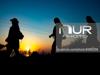 Group of ladies walking early in the morning towards former Moria Camp via the mountains. Silhouettes of walking refugees and migrants on th...