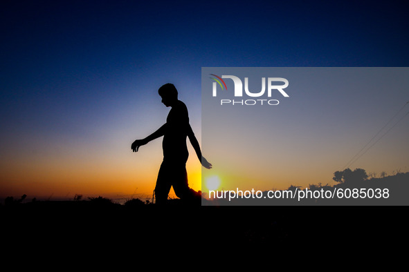 A single man walks early morning. Silhouettes of walking refugees and migrants on the hills early in the morning during the dawn and the sun...