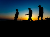 Group of male asylum seekers walk early in the morning towards Moria. Silhouettes of walking refugees and migrants on the hills early in the...