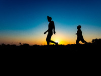 Shilhouette of a father with his child walking early in the morning. Silhouettes of walking refugees and migrants on the hills early in the...