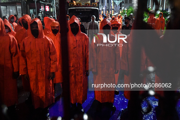 Police officers are seen wearing raincoats stand guard at gate of Royal Thai Police Headquarters during a protest of pro-democracy protester...