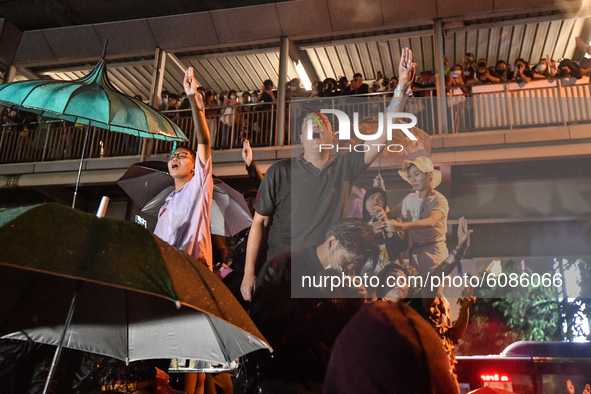 Pro-democracy protesters hold up three finger salute outside the Royal Thai Police Headquarters to protest the earlier arrest of protesters...