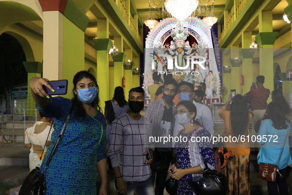 Visitors warring protective face mask take mobile selfie near of barricade of community puja pandal  ahead of the Hindu festival 'Durga Puja...