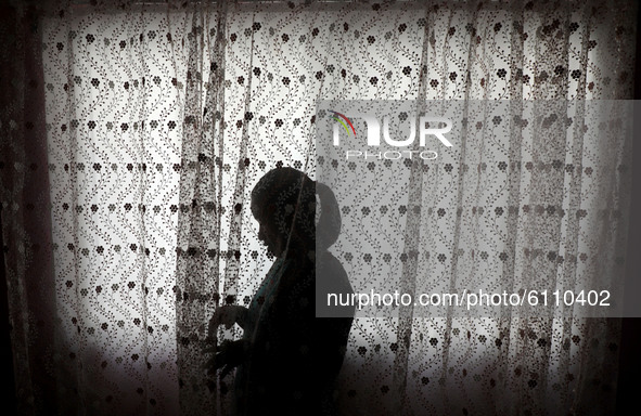 A Palestinian girl are seen behind a curtain at her home in Gaza city, on October 20, 2020.  