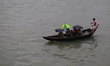 People cross over the Buriganga River by small wooden boats on a rainy day in Dhaka, Bangl...
