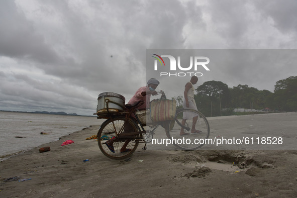 A fish vendor returned  home  after  cleans his bicycle and basket as dark clouds gather in the sky, in Guwahati, India on 24 October 2020. 