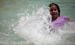 A Palestinian girl plays in a fountain basin to cool off during hot weather in Gaza City M...