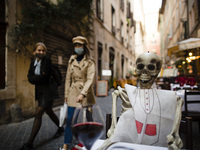  Tourists walk past a skeleton seen at a restaurant table to protest against the new national restriction to contain the coronavirus pandemi...