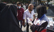 A female member of Iran Red Crescent Society (R) asks a man to wear a protective face mask...