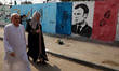 Palestinians walk past an anti-French President Emmanuel Macron mural painted by an artist...