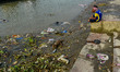 A municipal worker takes rest after his shift in front of debris filled bank of river Gang...