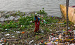 A lady makes her way through a garbage pile that rests at a river side in Kolkata post imm...