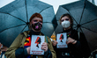 Two women are holding flyers and black umbrellas, in solidarity with Polish women, during...