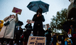 A woman is holding a black umbrella, in solidarity with Polish women, during the protest a...