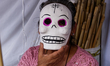 A woman poses with a Cardboard skulls mask  in  outdoor market, Cardboard skulls are used...