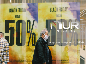 people walks by as Black Friday sales signs are seen in the city center of Cologne, on November 19, 2020.  (